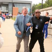 President Tom Haas walking arm-in-arm with a guest at the Jamie Hosford Football Center dedication.
